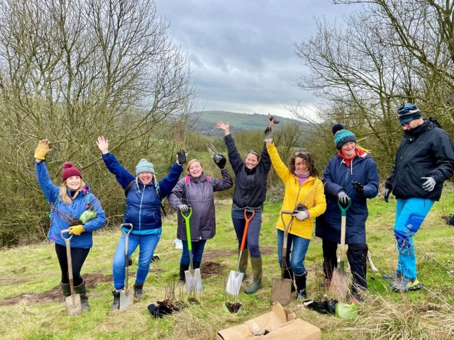 Image of people standing with spades celebrating planting trees